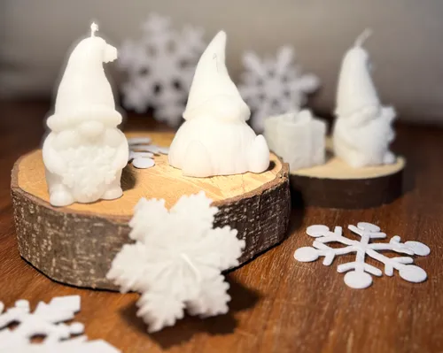 Weiße Kerzen in Form von Wichteln, sowie Schneeflocken