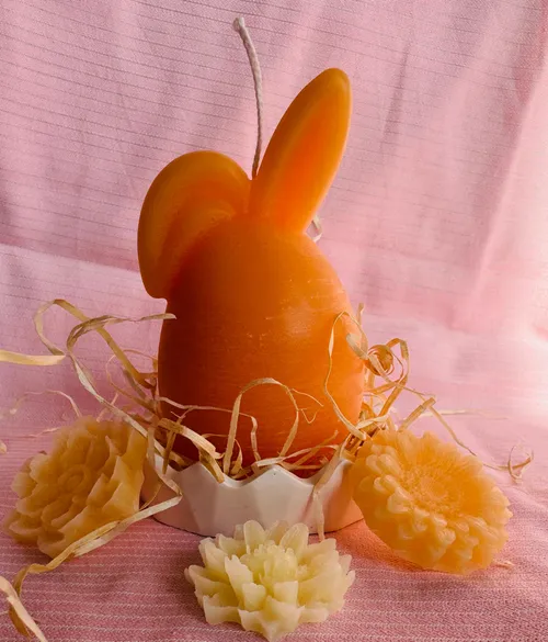 Ein Ei mit Ohren, umrandet von Blüten aus Wachs