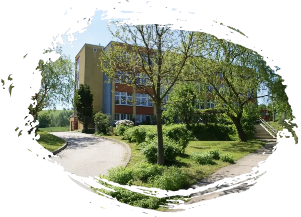 Das rot angestrichene Gebäude der Förderschule Polenz, davor eine grüne Wiese mit Bäumen und Sträuchern