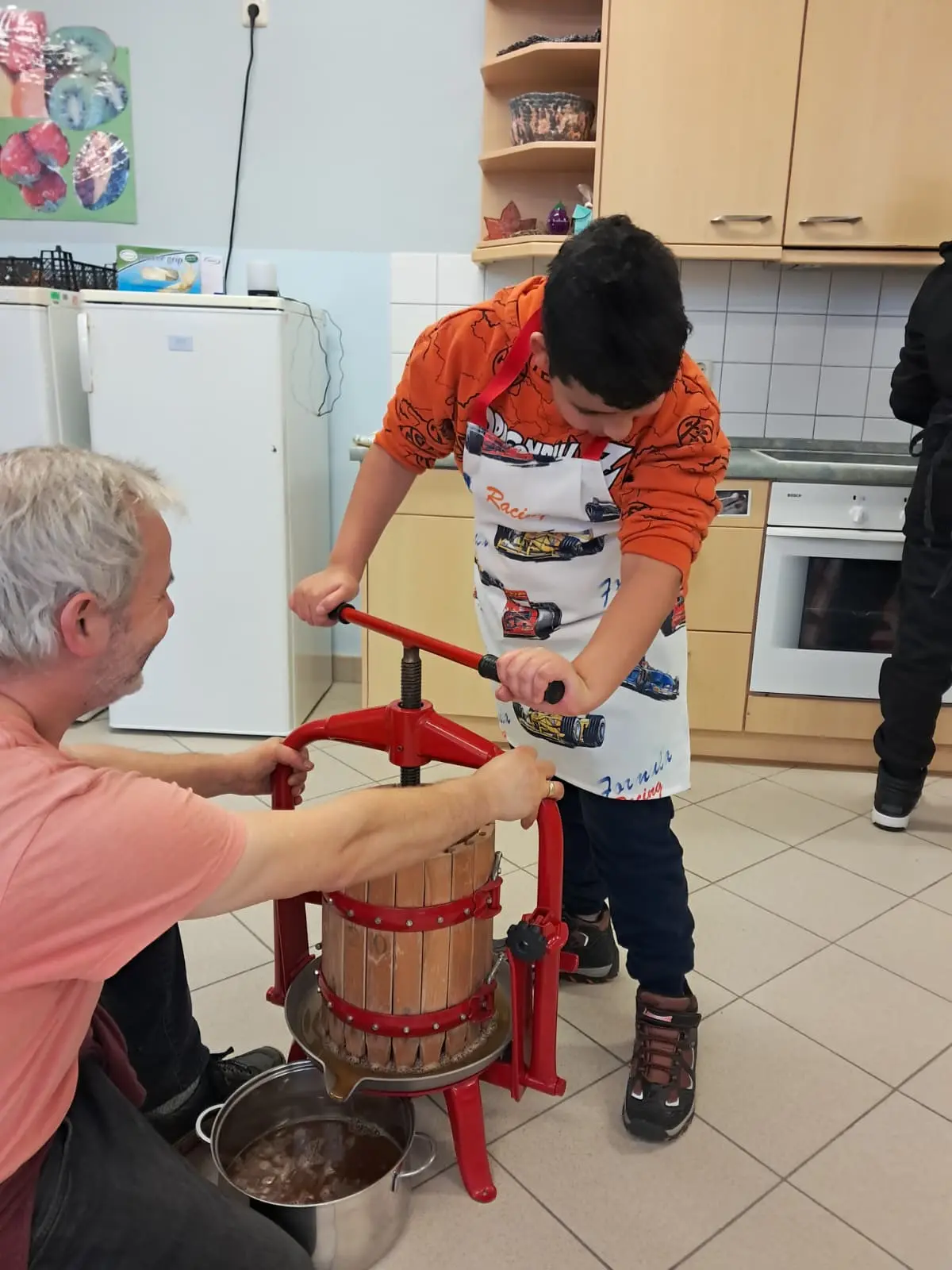 Die Apfelsaftpresse wird von zwei Personen bedient